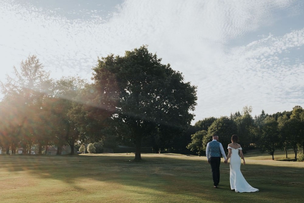bolton golf club wedding bride and groom walk on golf club at sunset