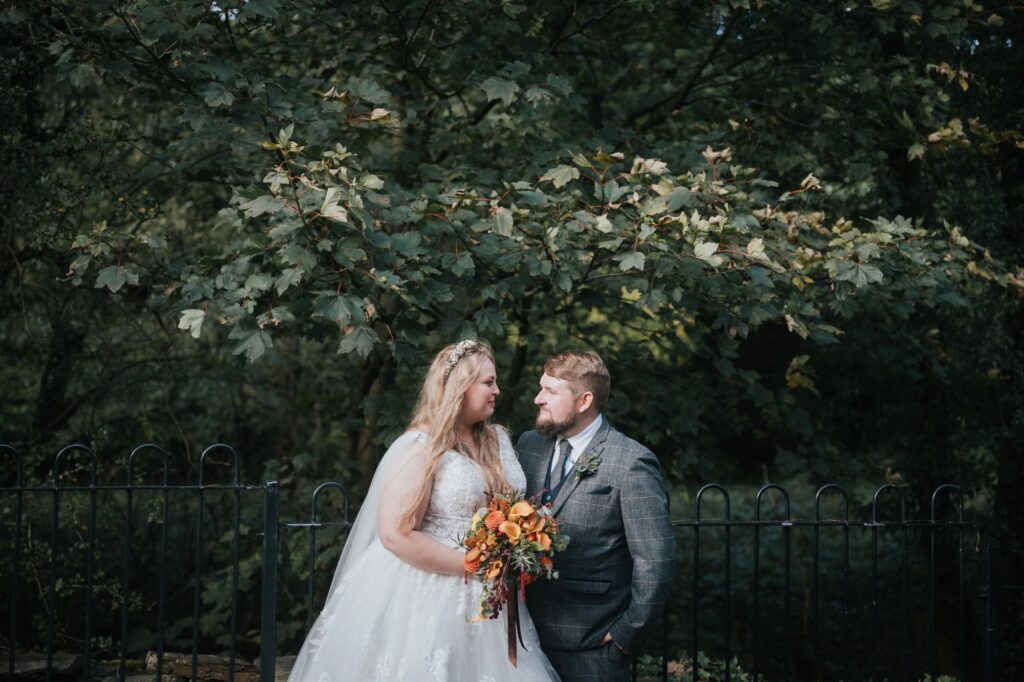 bride and groom in front of trees at their woodman thunderbridge wedding