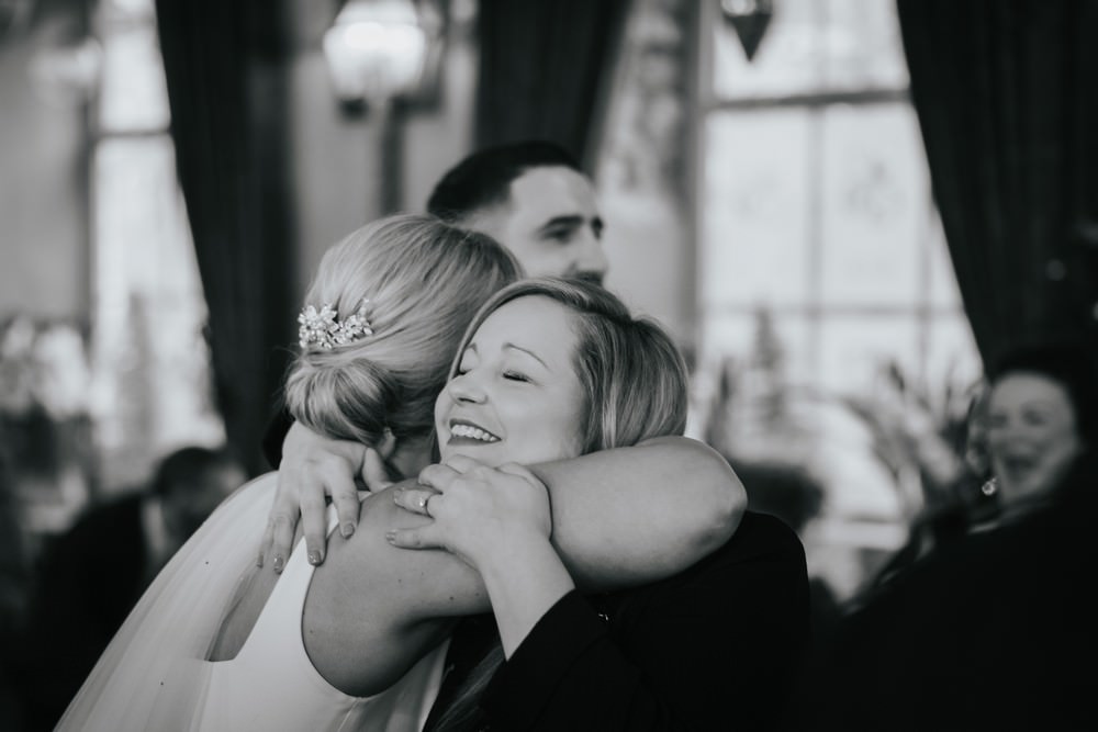 bride hugs guest black and white