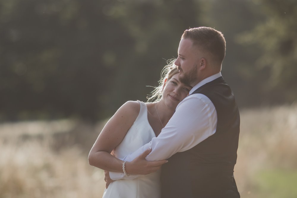 bride looking at camera while embracing groom at hazlewood castle wedding