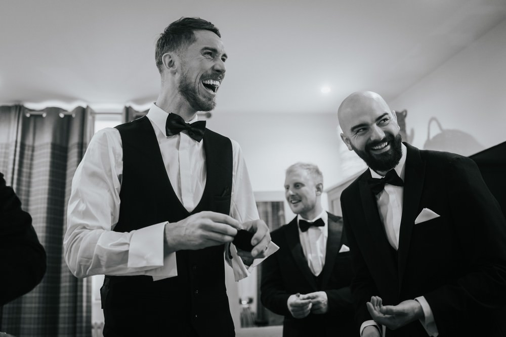 grooms men laughing in hotel room