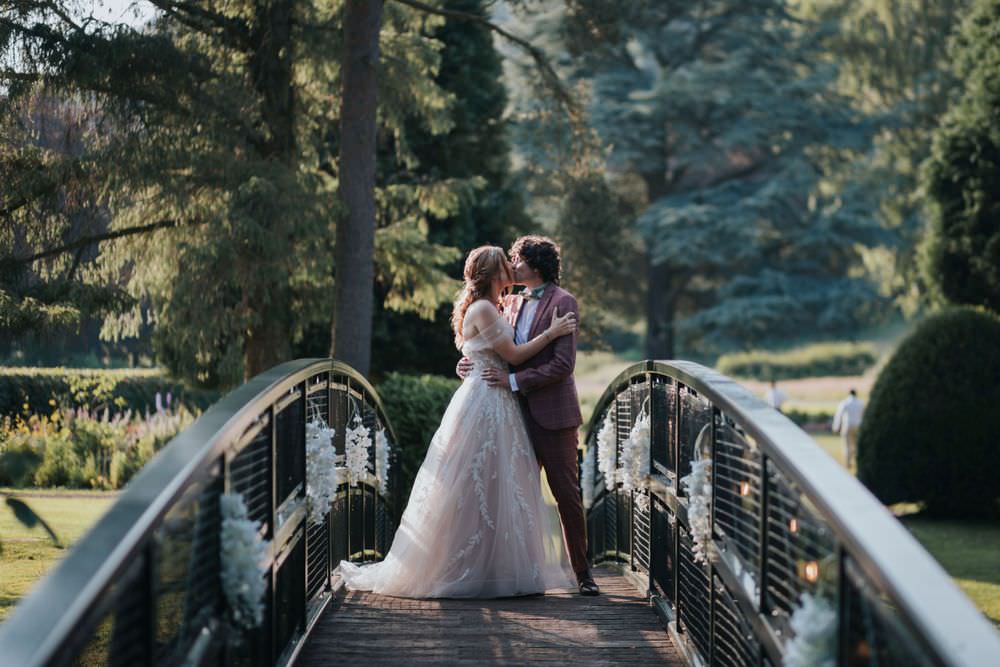 A bride and groom kissing on the brige at Hackness Grange