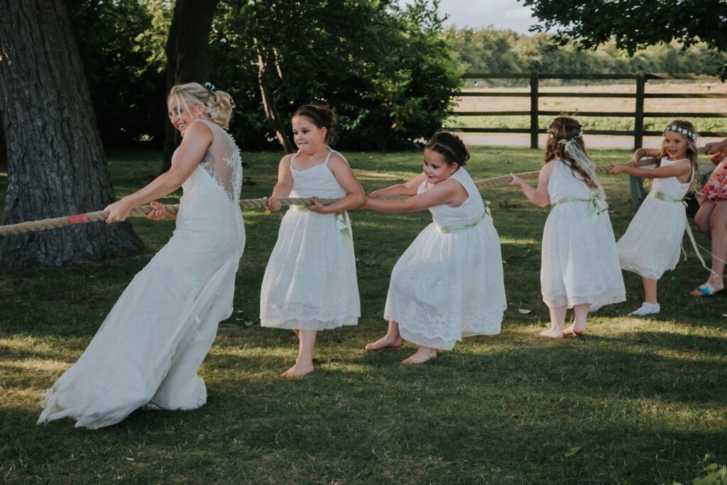 bride and flower girls pulling rope in tug of war